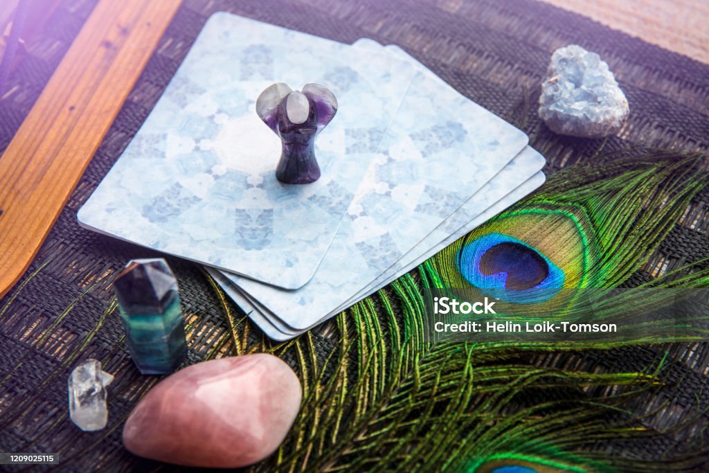 istockphoto-1209025115-1024×1024 Deck with divination homemade Angel cards on black table, surrounded with semi precious stones crystals. Selective focus on amethys crystal angel figurine.