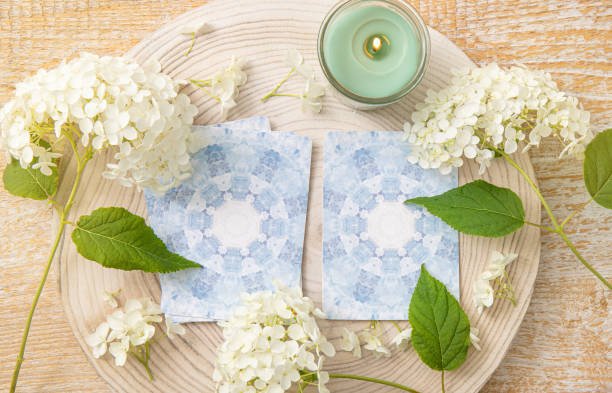 istockphoto-1631294772-612×612 Deck with homemade divination Angel cards on wood table with hydrangea flower for decoration. Home indoors candle burning.